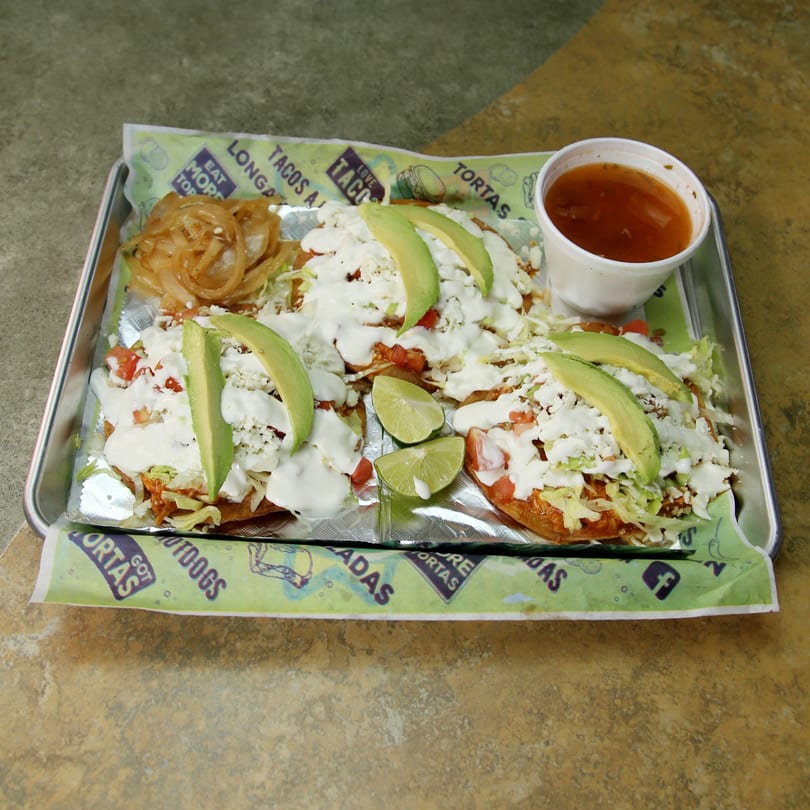 Three El Vagoncito Chilango sopes with avocado, cheese, and crema, served with onions and salsa.