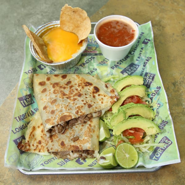 El Vagoncito Chilango's quesadilla with meat and melted cheese, served with avocado, lime, salsa, and queso.